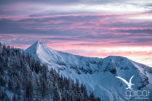 Das Abendrot taucht die Wolken über der verschneiten Kulisse der Steirischen Kalkspitze in eine herrliche rotblaue Abendstimmung